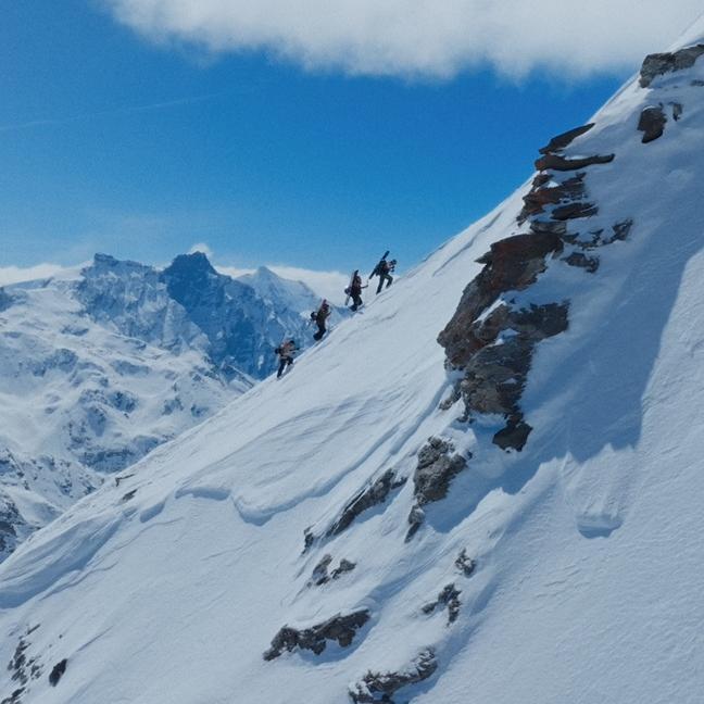 Eine Gruppe Bergsteiger erklimmt einen schneebedeckten Hang.